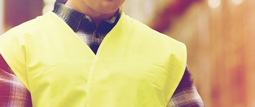 man in safety vest packing box at warehouse